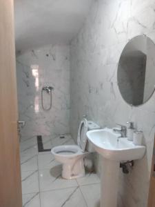 La salle de bains est pourvue d'un lavabo, de toilettes et d'un miroir. dans l'établissement Airport M V chambre stay, à Deroua