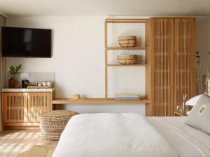 a bedroom with a white bed and a television at Walkers Beach in Plettenberg Bay