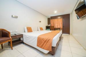 a hotel room with a large bed and a chair at Hotel Kalisma by Alia in Jakarta