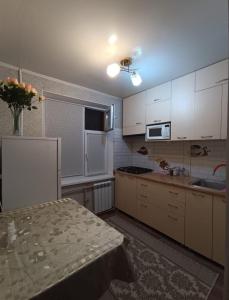 a kitchen with white cabinets and a table in it at Квартира LUX, Lux apartment in Taraz