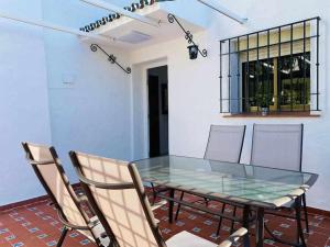 a dining room with a glass table and chairs at Acogedora casa con terraza y chimenea in Marbella