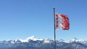 a flag on a pole with mountains in the background at Fortuna 403 in Leukerbad +3 photos