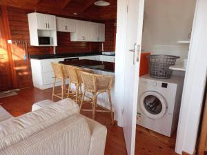 a kitchen with a washing machine and chairs in it at The beach cabin with pool in Port Alfred