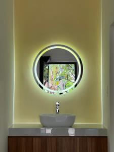 a bathroom with a sink and a round mirror at Color Inn - Homestay & Cafe in Ninh Hải