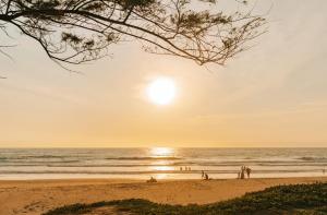 um grupo de pessoas na praia ao pôr do sol em Phuket Emerald Beach Resort em Praia de Karon