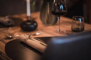 a wooden table with a black plate with a glass of wine at Hotel Lanerhof active/spa/balance in San Lorenzo di Sebato