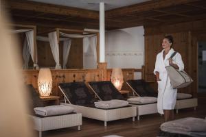 サン・ロレンツォ・ディ・セバートにあるHotel Lanerhof active/spa/balanceの椅子とテーブルが並ぶ部屋に立つ女性