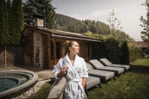 a woman in a robe standing next to a pool at Hotel Lanerhof active/spa/balance in San Lorenzo di Sebato