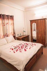 Un dormitorio con una cama con rosas rojas. en Vang Anh Homestay Hoi An en Hoi An