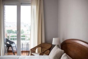 ein Schlafzimmer mit einem Bett und einem Stuhl sowie einem Balkon in der Unterkunft Piso Avenida de los Castros - Sardinero in Santander