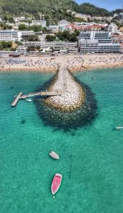 uma vista aérea de uma praia com dois barcos na água em SESIMBRA SOL em Sesimbra