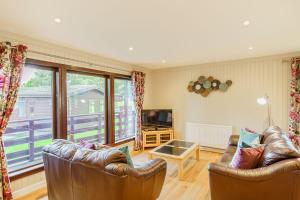 a living room with two leather couches and a television at Bluebell Lodge 10 with Hot Tub in Newton Stewart