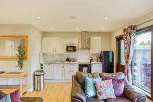 a living room with a couch and a kitchen at Bluebell Lodge 10 with Hot Tub in Newton Stewart