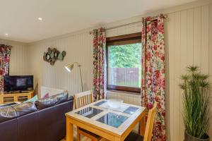 a living room with a table and a couch at Bluebell Lodge 10 with Hot Tub in Newton Stewart +7 photos