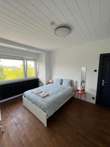 a white bedroom with a bed and a window at Tram station rooms by CityPillow since 2019 in Hesperange