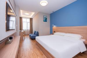 Un dormitorio con una gran cama blanca y una pared azul en Future Shangju Hotel, en Shanghái
