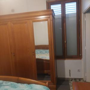 1 dormitorio con armario de madera y espejo en Une chambre dans une petite appartement a côté de paris la défense, en Colombes