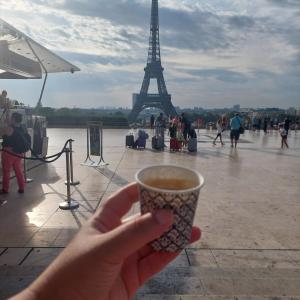 una persona sosteniendo una taza de café frente a la torre Eiffel en Une chambre dans une petite appartement a côté de paris la défense, en Colombes