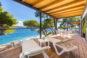 une terrasse en bois avec une table et des chaises et l'océan dans l'établissement Arena Stoja Camping Homes, à Pula