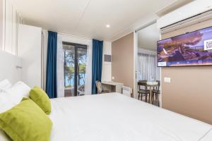 a hotel room with a large bed and a flat screen tv at Arena Stoja Camping Homes in Pula