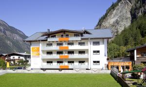 a large white building with a mountain in the background at Top Tirol Appartement in Längenfeld