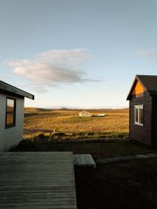 ein kleines Haus neben einem Feld mit Scheune in der Unterkunft Árbúðir in Kerlingarfjoll
