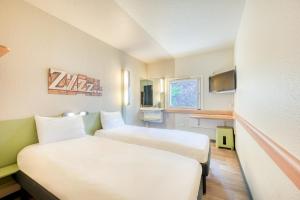 une chambre d'hôtel avec deux lits et une cuisine dans l'établissement ibis budget Versailles - Trappes, à Trappes