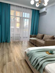 a bedroom with blue curtains and a bed and a couch at ЖК Champion с новым ремонтом in Astana