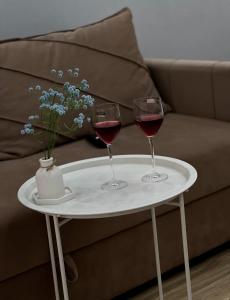 two glasses of wine on a white table with a couch at ЖК Champion с новым ремонтом in Astana
