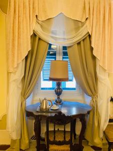 a table with a lamp in front of a window at Palazzo Lari Luxury Accommodation in Sarzana