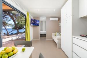 a kitchen and living room with a table with a bowl of fruit on a plate at Arena Stoja Camping Homes in Pula