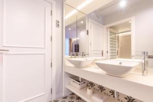 a bathroom with two sinks and a mirror at Serennia Fira Gran Via Exclusive Rooms in Hospitalet de Llobregat