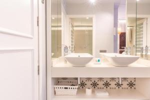 a bathroom with two sinks and a mirror at Serennia Fira Gran Via Exclusive Rooms in Hospitalet de Llobregat
