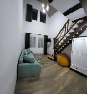 a living room with a blue couch and a staircase at PENSIUNEA CASTELANA in Racoşu de Jos