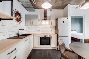 a kitchen with white cabinets and a sink and a table at Modern and Chic Apartments at Ferrum near Wembley Park in London