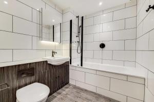 a bathroom with a toilet and a sink and a tub at Modern and Chic Apartments at Ferrum near Wembley Park in London