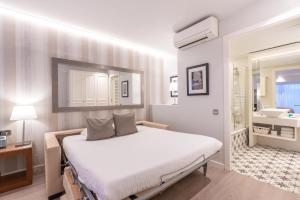Serennia Fira Gran Via Exclusive Rooms في لوسبيتاليت دي يوبريغات: غرفة نوم بيضاء مع سرير وحمام
