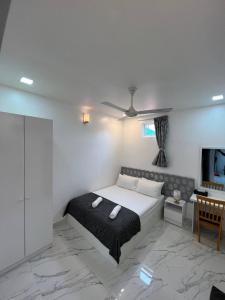 a white bedroom with a bed and a tv at Empyrean Stay, Maldives in Thulusdhoo
