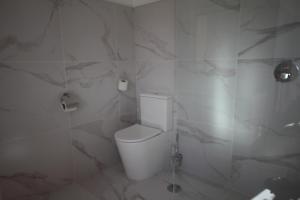 a bathroom with a white toilet and marble walls at B&B Villa Branca Barreiros AL98139 in Barreiros