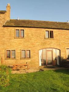 uma casa de tijolos com um banco à frente em Midsummer Barn em Darwen