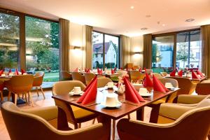 a restaurant with tables and chairs with red pillows at Hotel Rittergut Stoermede in Geseke