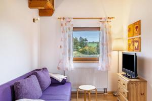sala de estar con sofá púrpura y ventana en Ferienhaus Katrin en Bad Urach