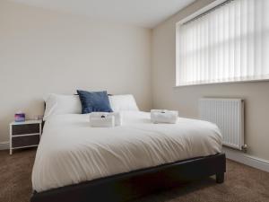 a bedroom with a large white bed with two boxes on it at Pass the Keys Modern and Cozy Kirkby Retreat Parking Sleeps 5 in Knowsley