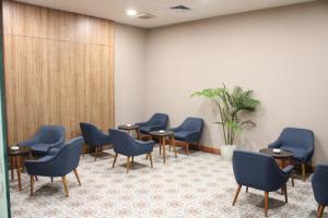 uma sala de espera com cadeiras e mesas azuis em Cordia Hotel Banjarmasin - Hotel Dalam Bandara em Pulaubiruang