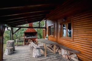 eine Holzterrasse mit einer Bank und einem Kamin in der Unterkunft Le'Klet Holiday House in Donji Kraj