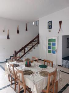 a dining room with a table and chairs and a staircase at Dar louzir à Tazarka in Tazarka