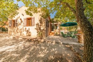 ein Haus mit einem Tisch und einem Sonnenschirm in der Unterkunft L'Oustaou Dou Verdoun - Avec grand jardin in Régusse + 5 Fotos