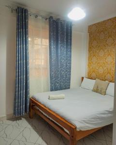 a bed in a room with blue curtains at Blèu Mustard Two Bedroom in Nanyuki