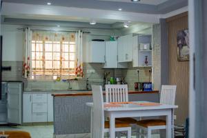 a kitchen with white cabinets and a table and chairs at Blèu Mustard Two Bedroom in Nanyuki