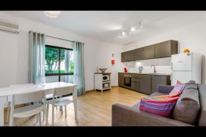 eine Küche und ein Wohnzimmer mit einem Sofa und einem Tisch in der Unterkunft Falésia Modern Flat W/Balcony & Pool by LovelyStay in Albufeira